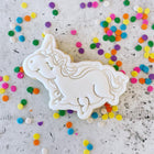 White Sleeping Unicorn Cookie on bench of rainbow confetti